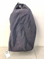 Side view of black canvas duffle backpack showing overall size and material