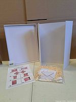 white cardboard gift box opened, assembly chart sheet, bag of filler and gift card displayed