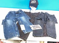 Overview of two girls denim jeans, one women’s corduroy jeans, and black baseball cap