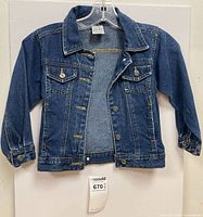 Front view of denim jacket on hanger showing buttons, pockets, cuffs
