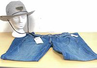 Jeans with tag alongside hat on form