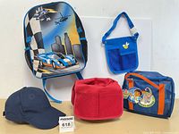 Front view of all five items: backpack, mini duffle, tool belt, red tool bucket, cap