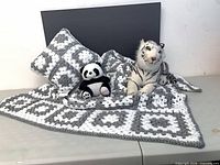 Afghan spread on table with pillow, panda and tiger plush displayed