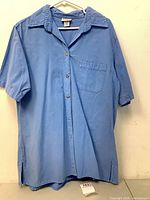 Front view of blue short-sleeve shirt showing buttons, pocket and hem