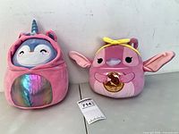 Both plush toys side by side against wall showing size difference