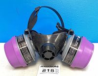 Front view of North 7700-305 respirator showing mask body, head strap and attached purple filter cartridges