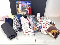 Overview showing fabrics, patterns, electric scissors, thread cone and books