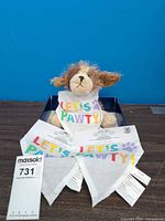 Plush dog toy wearing bandana with two additional bandanas displayed