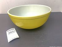 Side view of yellow Pyrex mixing bowl with lot tag