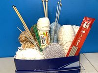 Box containing assorted yarn skeins and needles
