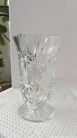 Front view of clear cut glass pedestal vase showing carved patterns and flared rim
