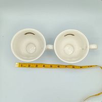Top view of both winking face cups showing interior and diameter with measuring tape