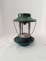 Front view of green Coleman propane lantern on base