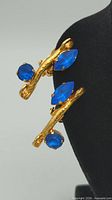 Front view showing goldtone branch design with round and marquise blue rhinestones