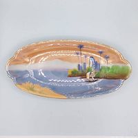 Full view of long oval Noritake dish with painted scene and gold rim