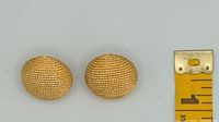 Front view of both ribbed gold-tone earrings beside ruler