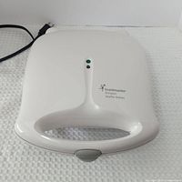 Closed waffle maker showing exterior housing and cord