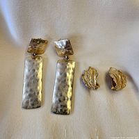 Both pairs of earrings laid out on fabric
