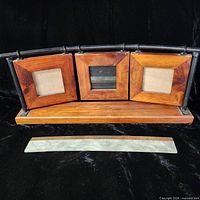 Front view showing three square wood frames on metal rail and wood base with ruler for scale