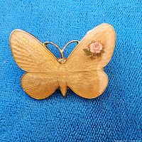 Front view of yellow butterfly brooch with painted rose