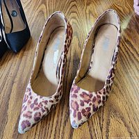 Top view of both pumps showing leopard print pattern, pointed toes, worn insoles
