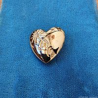 Front view of gold tone heart pin on blue cloth