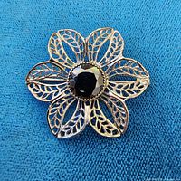 Front view of silver-tone filigree flower brooch with black center stone