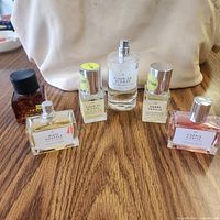 Six perfume bottles arranged on wooden surface showing front labels and caps