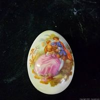 Closed oval trinket box showing courting couple scene on lid