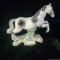 Front left view of porcelain horse figurine on decorative base