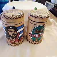 Front view of both wooden souvenir containers showing artwork and lids