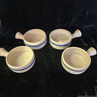 Four handled soup bowls arranged on dark backdrop