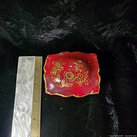 Top view of red porcelain lid beside ruler