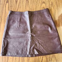 Front view of brown faux leather mini skirt laid flat