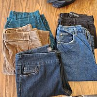 Five folded pairs of pants laid out showing colors and materials