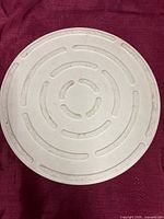 Top view of round ceramic pizza stone showing ventilation groove pattern