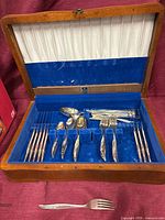 Open Birks wood chest showing flatware pieces in blue velvet interior