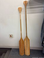 Full view of both wooden paddles leaning against wall