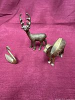 Stag, swan, elephant brass figurines grouped on fabric