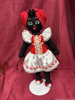 Front view of cloth doll on stand showing dress, shoes, overall appearance