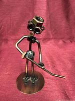 Front view of welded metal figure holding rod on round base
