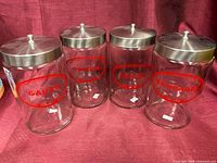 Four glass jars with red labels and metal lids