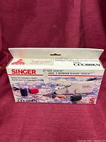 Front view of Singer Handy Stitch CEX300KN retail box displaying product image and branding