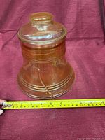Full view Liberty Bell amber glass jar with lid and tape measure showing diameter