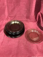 Stack of smoked amber glass plates beside single plate