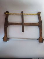 Full view of wooden bow saw showing frame, stretcher, cord and blade