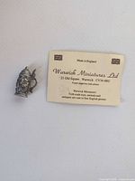 Front view of pewter 1/12 scale tankard beside maker card