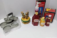 Overall lot showing slider press, ceramic condiment dispensers, burger pick holder and boxes
