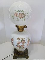 front view of milk glass parlor lamp showing floral paint and metal base