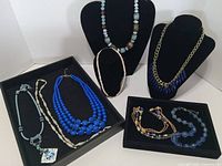 All seven necklaces displayed on stands and in trays